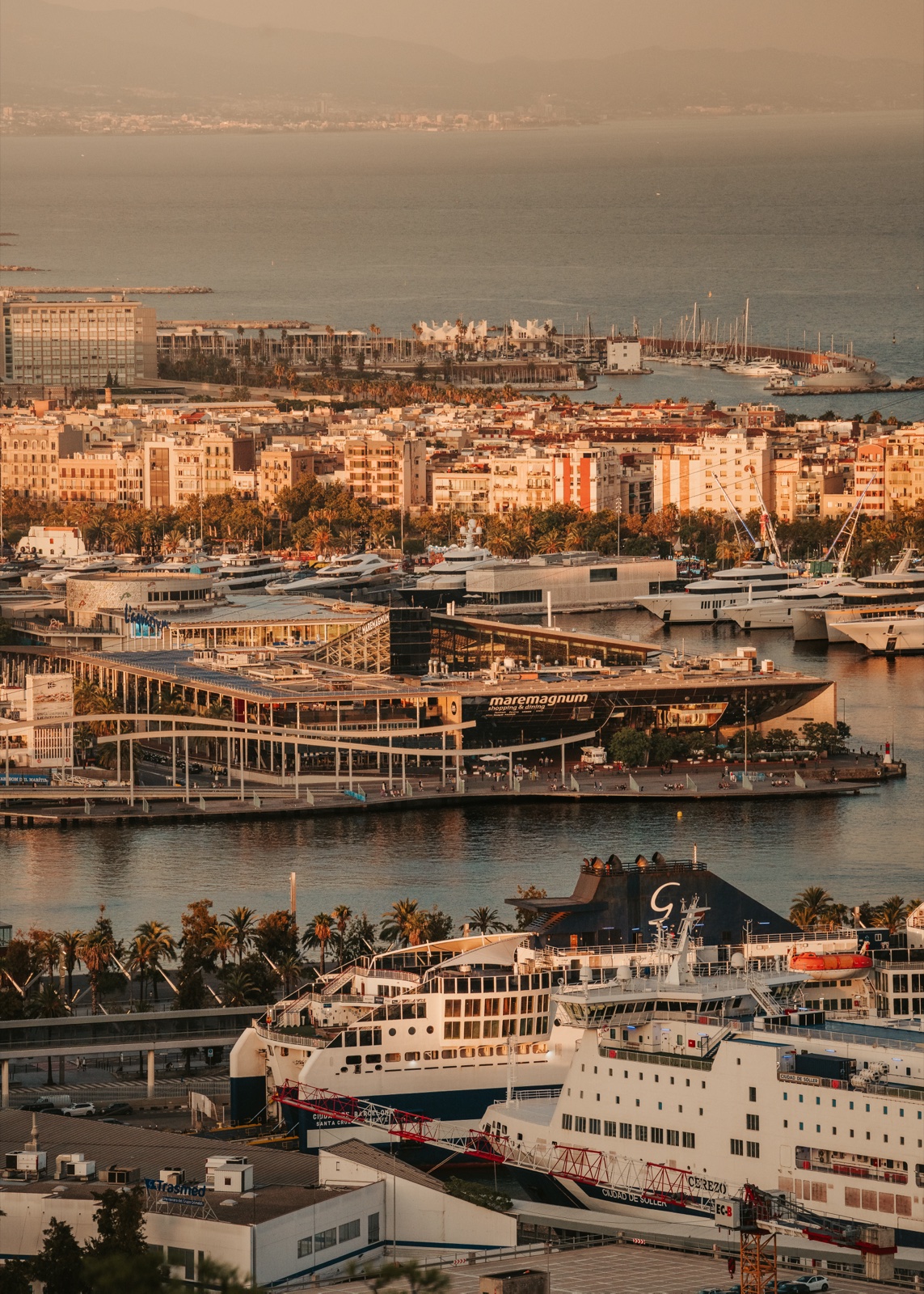 Ferries in the harbour of Port Vell, with the city and the sea beyond