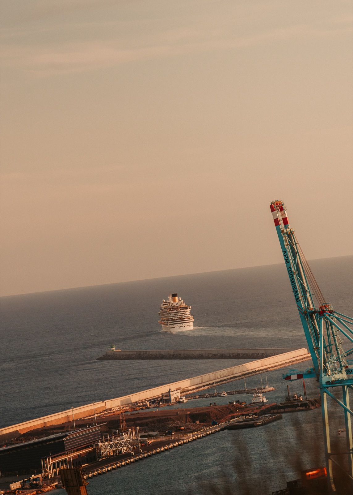 A cruise ship leaving the port, beside a harbour crane